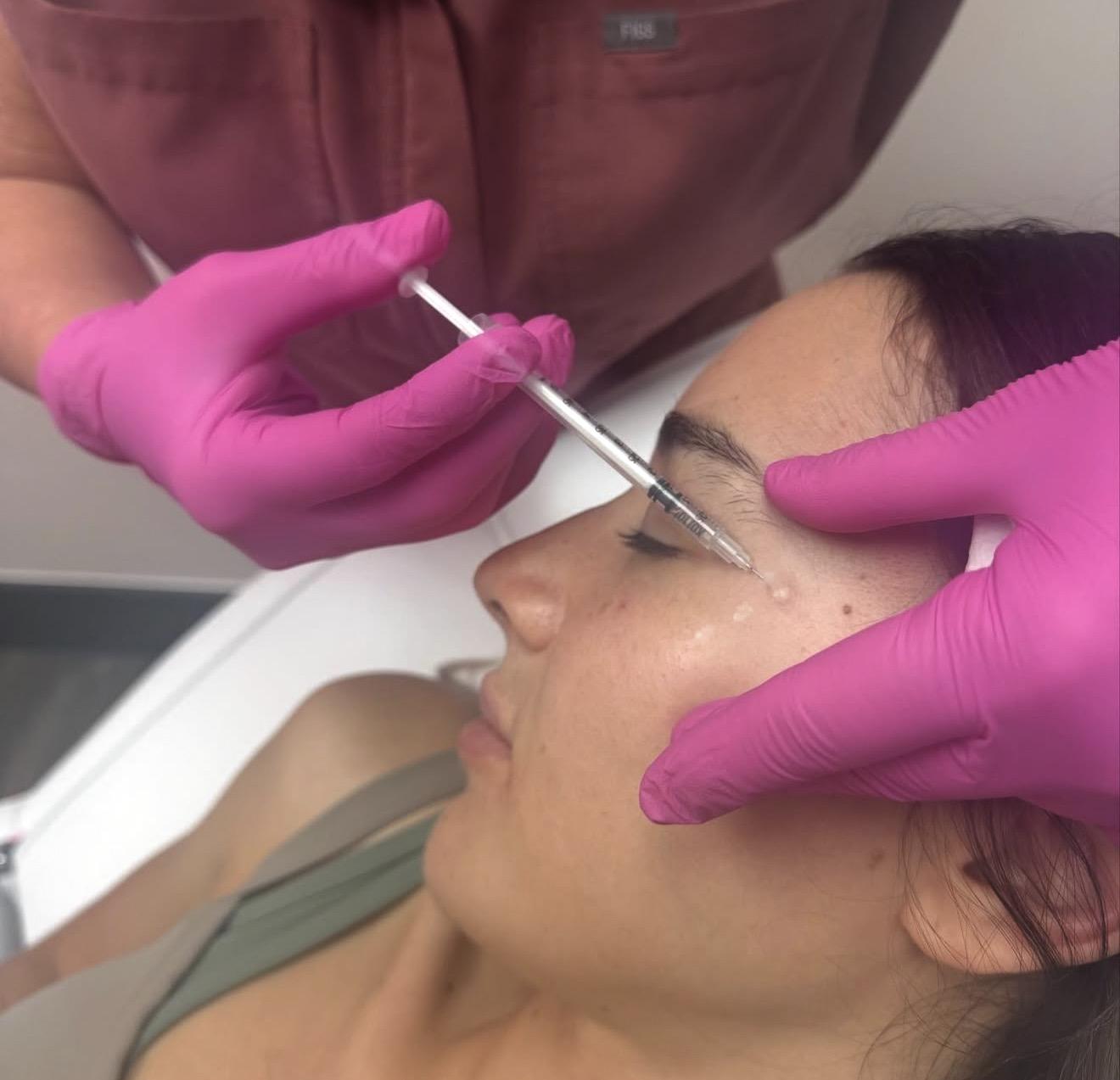 Aesthetician injecting Tox into a client's face